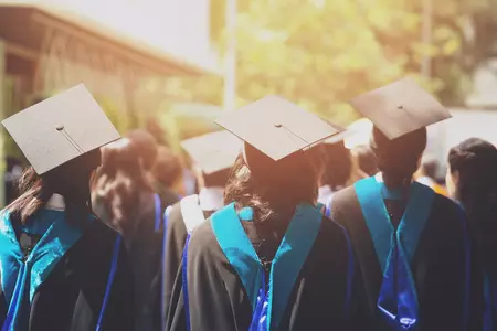 Students throwing graduation caps in air. 