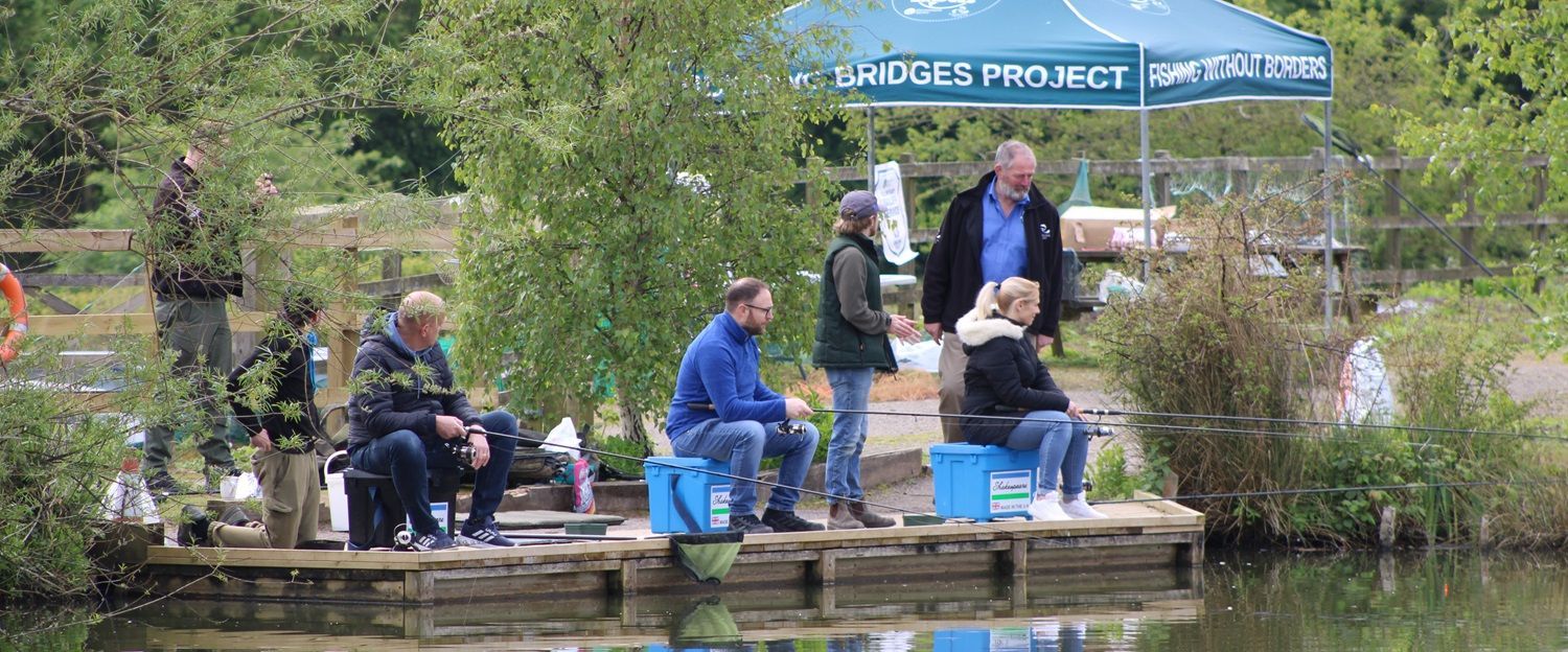 Group of people fishing on bank of pond